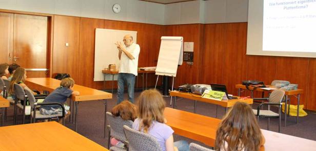 Ein Mann hält einen Vortrag vor einer Gruppe von Kindern in einem Klassenzimmer.
