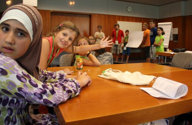 Eine Gruppe von Kindern sitzt an einem Tisch in einem Klassenzimmer.