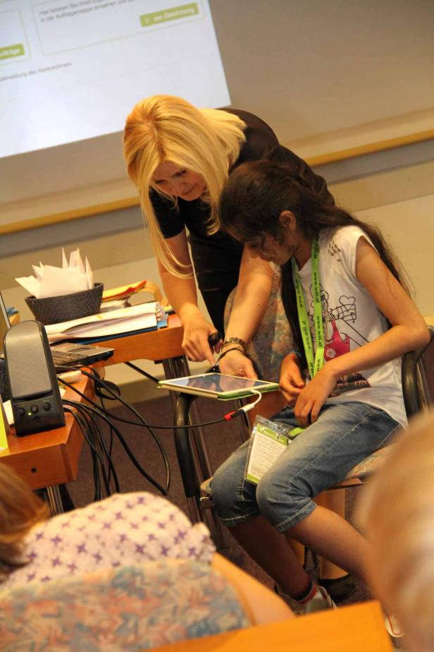Eine Frau hilft einem Mädchen bei der Bedienung eines Tablets.