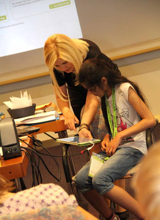 Eine Frau hilft einem Mädchen bei der Bedienung eines Tablets.