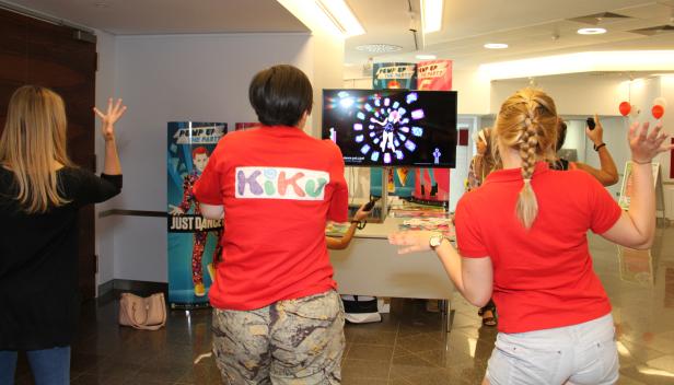 Mehrere Personen spielen „Just Dance“ vor einem Bildschirm.