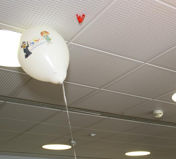Ein weißer Ballon mit einer Zeichnung schwebt unter einer Decke.