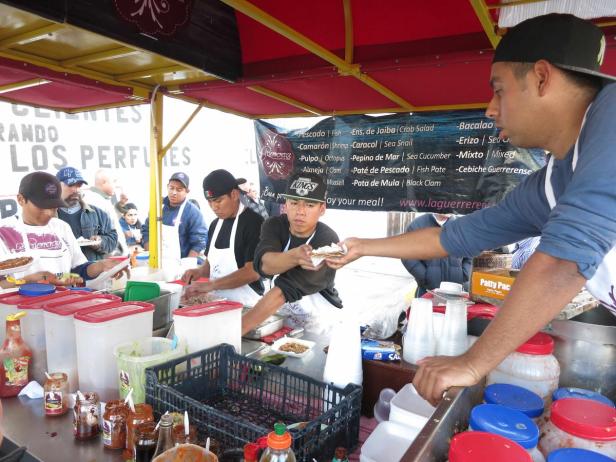 Mehrere Männer arbeiten an einem Stand, der Meeresfrüchte verkauft.