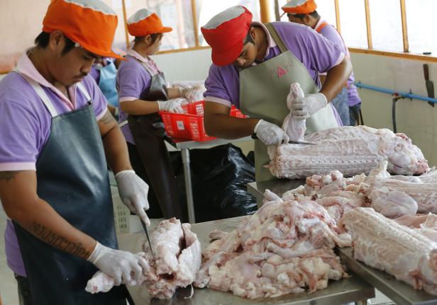 Mehrere Arbeiter verarbeiten Fleisch in einer Produktionsstätte.