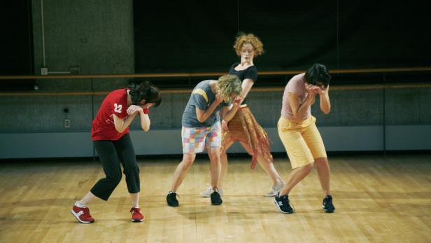 Eine Gruppe von vier Tänzern führt eine synchrone Choreografie auf einer Bühne auf.