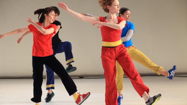 Eine Gruppe von Tänzern in farbenfroher Kleidung führt eine synchrone Choreografie auf.