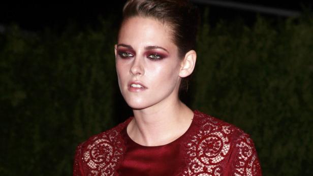 Kristen Stewart mit dunklem, auffälligem Augen-Make-up und einem roten Kleid mit Spitze.