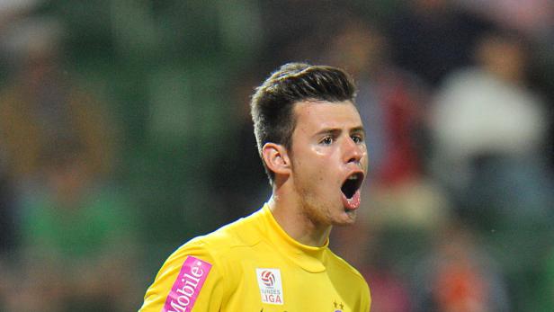 Ein Fußballspieler in gelber Sportkleidung schreit auf dem Spielfeld.