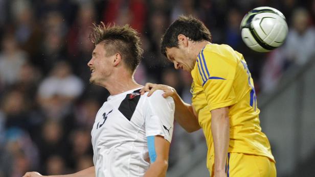 Ein Fußballspieler legt einem anderen im gelben Trikot die Hand auf die Schulter.