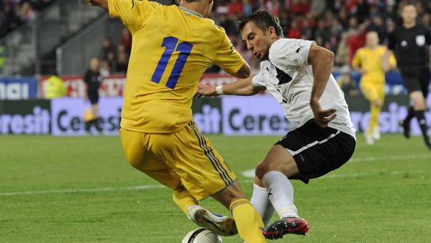 Zwei Fußballspieler kämpfen um den Ball auf dem Spielfeld.