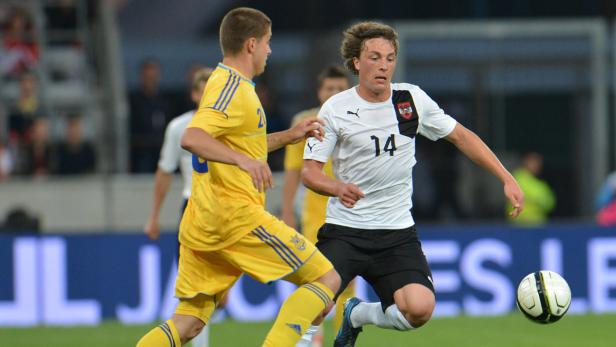 Ein Fußballspieler im weißen Trikot mit der Nummer 14 dribbelt den Ball.