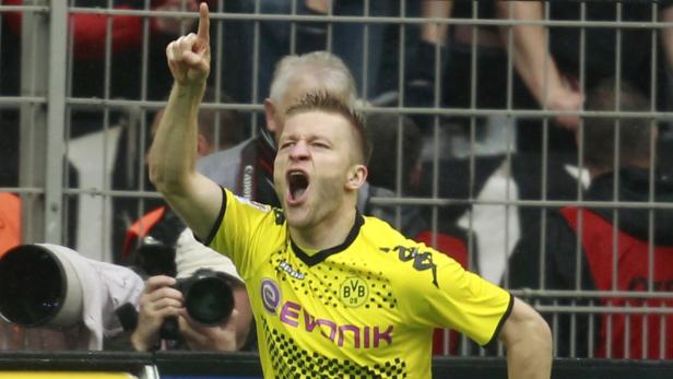 Ein jubelnder Fußballspieler im gelben Trikot von Borussia Dortmund zeigt mit dem Finger nach oben.