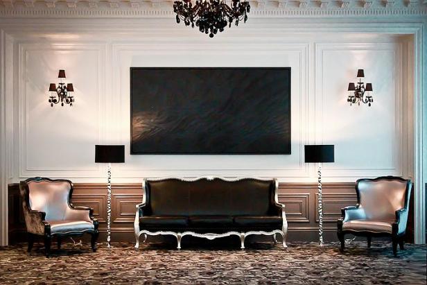 Ein elegant eingerichteter Raum mit einem Sofa, zwei Sesseln und einem großen Gemälde.