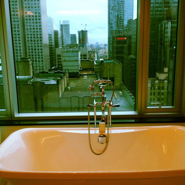 Eine Badewanne vor einem Fenster mit Blick auf eine Stadtlandschaft.
