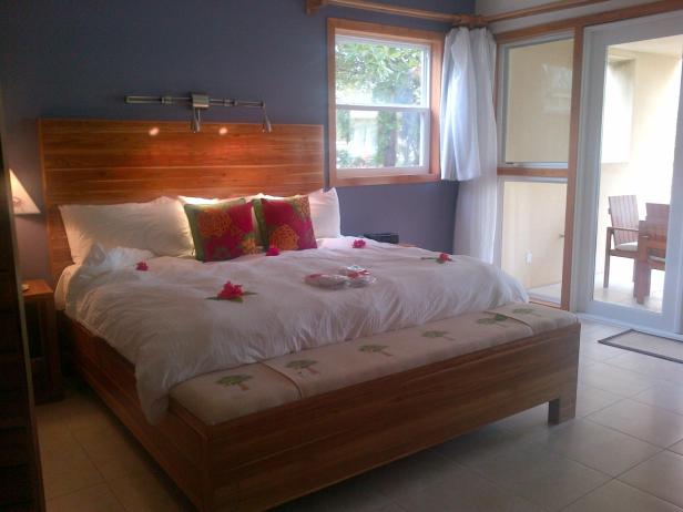 Ein Schlafzimmer mit einem großen Holzbett und Hibiskusblüten auf der Bettdecke.