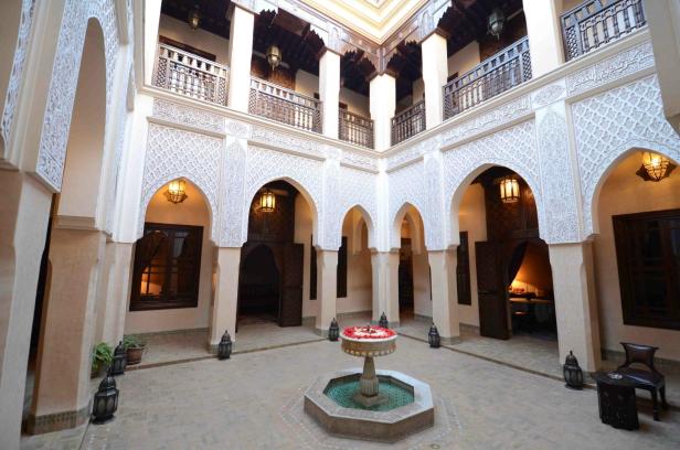 Ein Innenhof mit einem Brunnen in der Mitte, umgeben von Bögen und dekorativen Elementen.