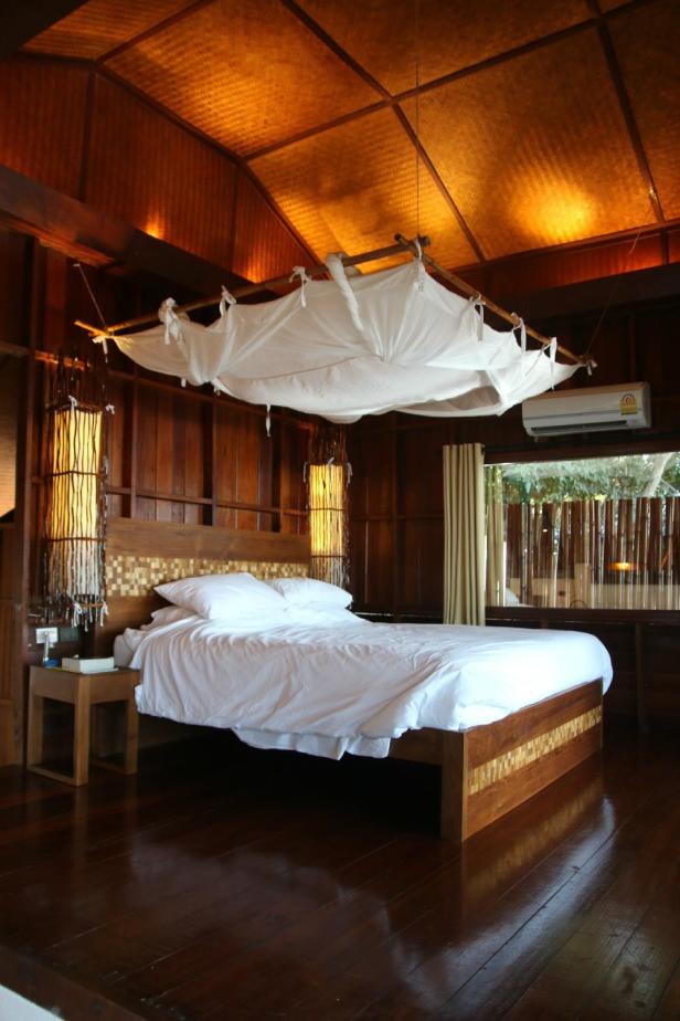 Ein Schlafzimmer mit Holzwänden und einem Himmelbett mit weißem Stofftuch.