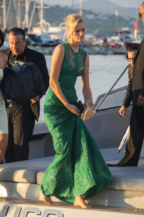 Eine barfüßige Frau in einem grünen Kleid verlässt ein Boot.