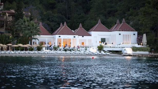 Ein Strandrestaurant mit Liegestühlen am Wasser bei Dämmerung.