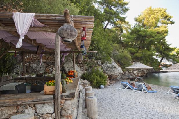 Ein Strand mit Liegestühlen vor einem kleinen, rustikalen Strandrestaurant.