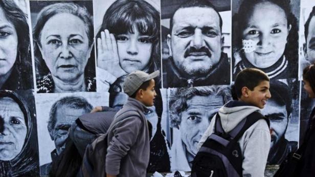Inside Out, Artocracy in Tunisia Zwei Jungen gehen an einer Wand mit Schwarz-Weiß-Porträts vorbei.