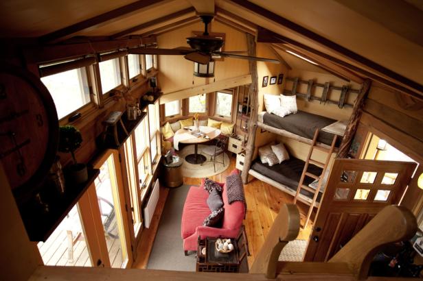 Blick in ein gemütliches Baumhaus-Interieur mit Betten, Sofa und Esstisch.