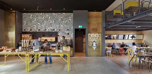 Gäste bedienen sich am Frühstücksbuffet in einem modern eingerichteten Raum.