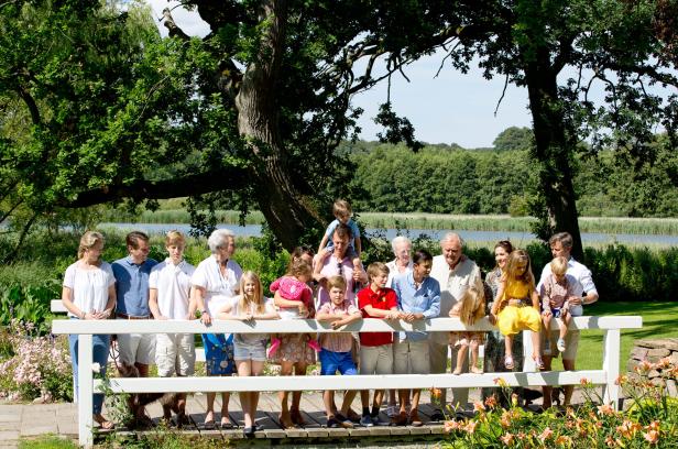 Die dänische Königsfamilie posiert auf einer Brücke vor einer malerischen Landschaft.