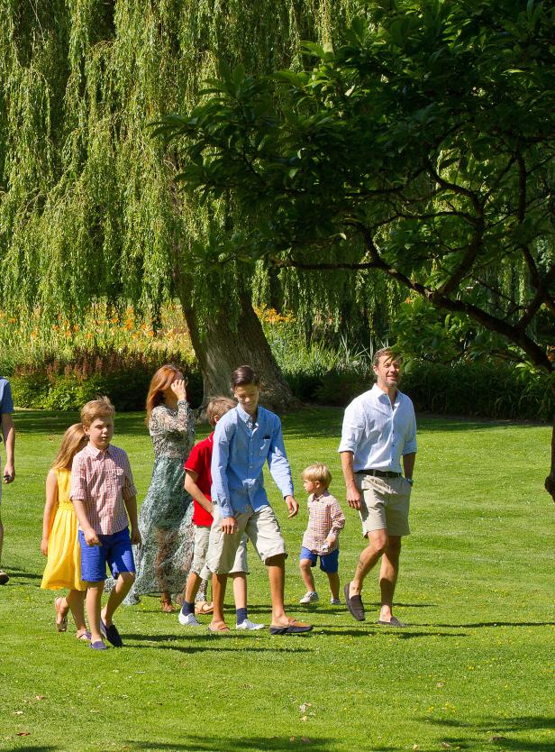 Eine Familie geht an einem sonnigen Tag über eine grüne Wiese.