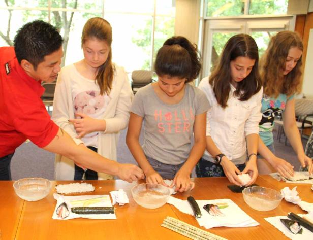 Eine Gruppe von Jugendlichen lernt, wie man Sushi zubereitet.