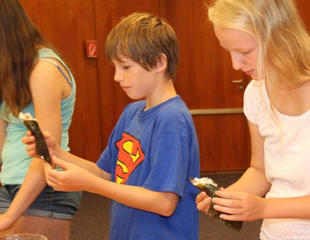 Zwei Kinder betrachten selbstgemachtes Sushi.