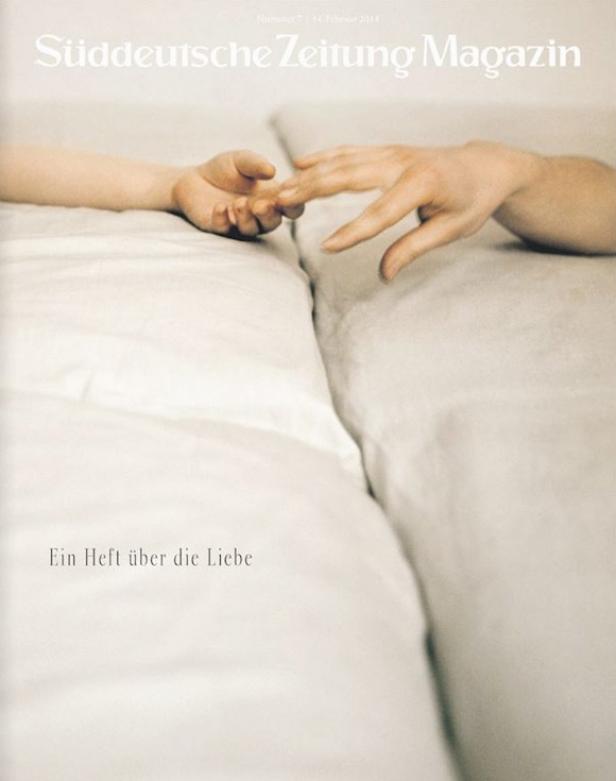 Zwei Hände berühren sich zärtlich auf einem weißen Kissen.