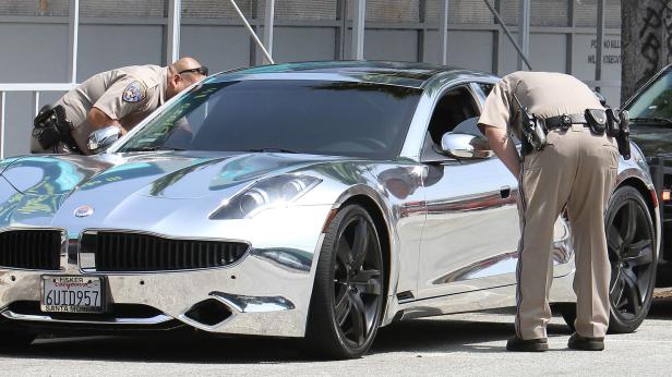 Zwei Polizisten inspizieren einen verspiegelten Fisker Karma.