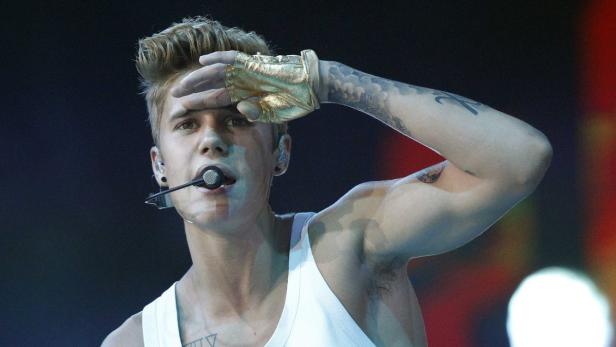 Justin Bieber mit goldenem Handschuh und Mikrofon während eines Auftritts.