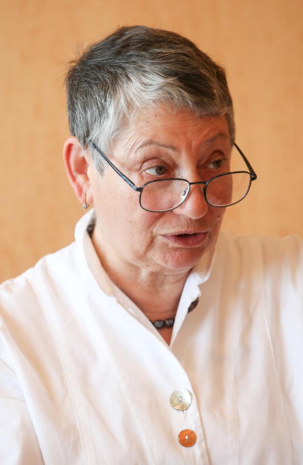 Eine Frau mit Brille und kurzem, grauem Haar schaut zur Seite.