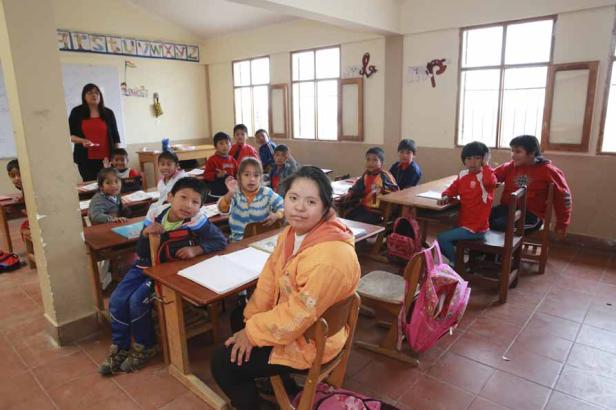 Eine Lehrerin steht vor einer Klasse von Kindern in einem Klassenzimmer.