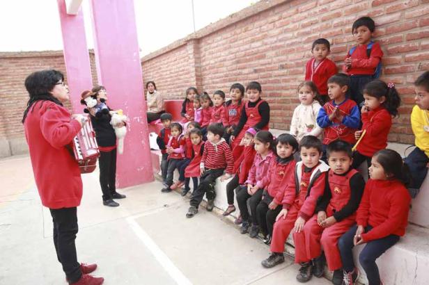 Eine Frau spielt Akkordeon und führt Handpuppen für eine Gruppe Kinder auf.