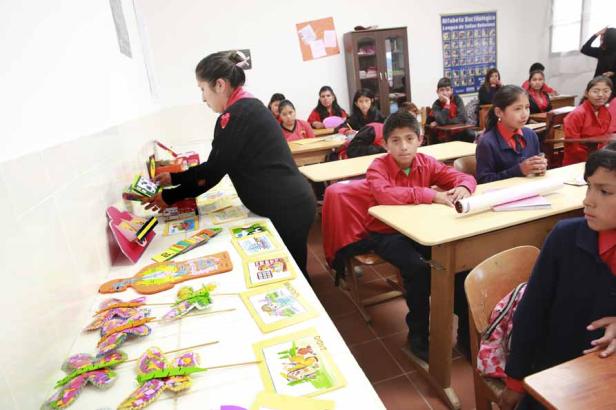 Eine Lehrerin präsentiert Lehrmaterialien vor einer Klasse von Schülern in einem Klassenzimmer.
