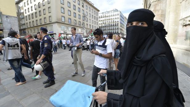Eine Frau mit Niqab auf einer belebten Straße in Wien.