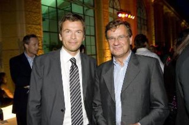 Zwei Männer in Anzügen posieren für ein Foto.