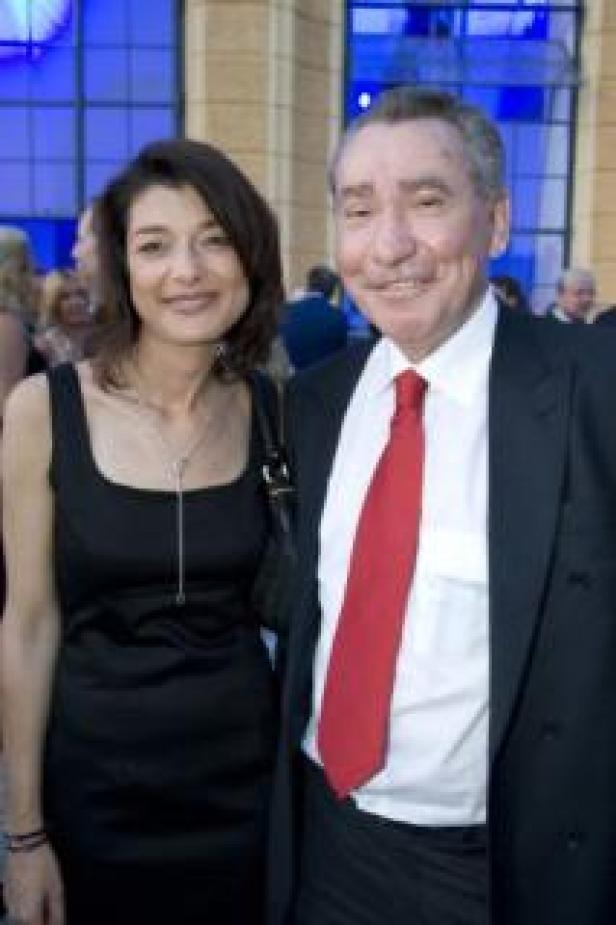 Eine Frau in einem schwarzen Kleid und ein Mann mit roter Krawatte posieren für ein Foto.