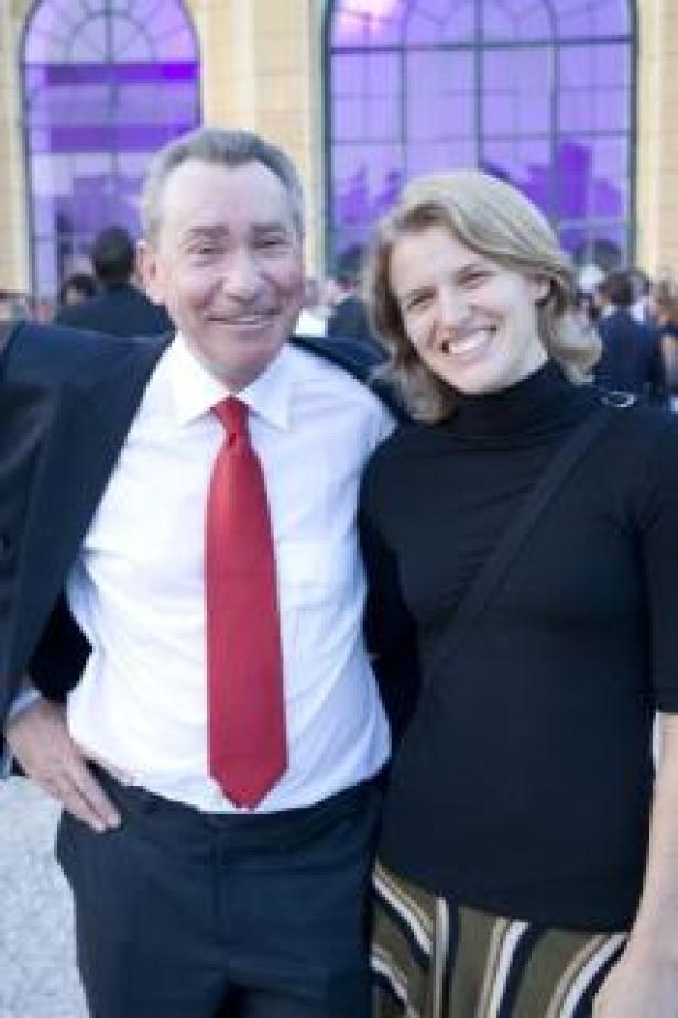 Ein Mann mit roter Krawatte und eine Frau lächeln in die Kamera.