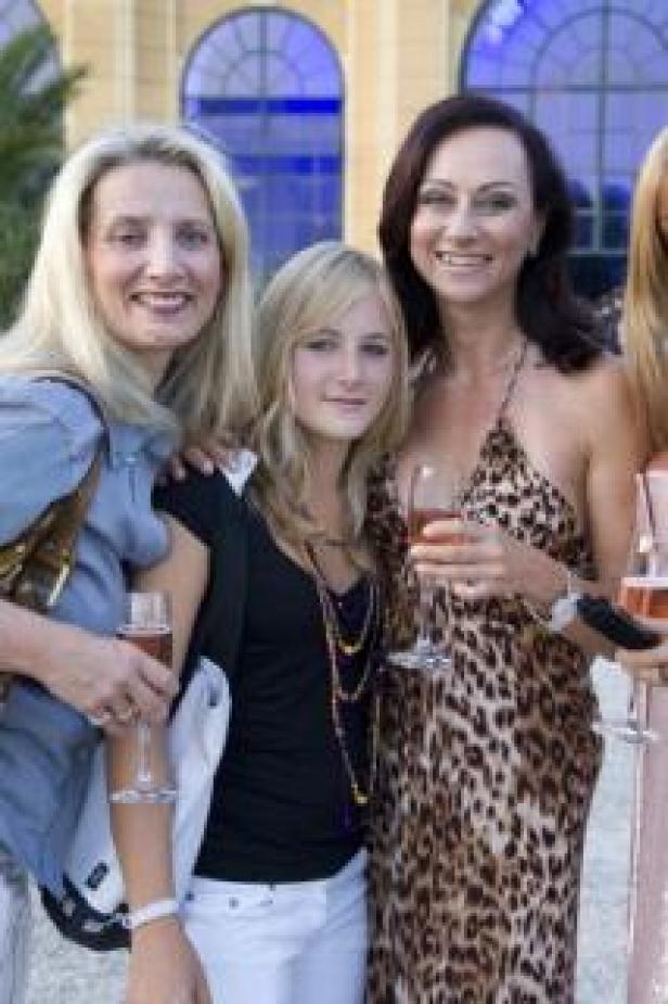 Drei Frauen posieren mit Getränken in der Hand für ein Foto.
