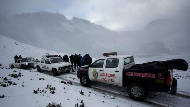 Mehrere Fahrzeuge der peruanischen Nationalpolizei stehen in einer verschneiten Berglandschaft.