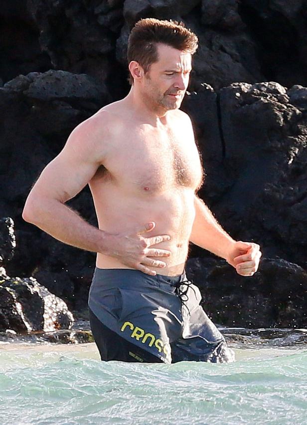 Hugh Jackman steht im Wasser am Strand.