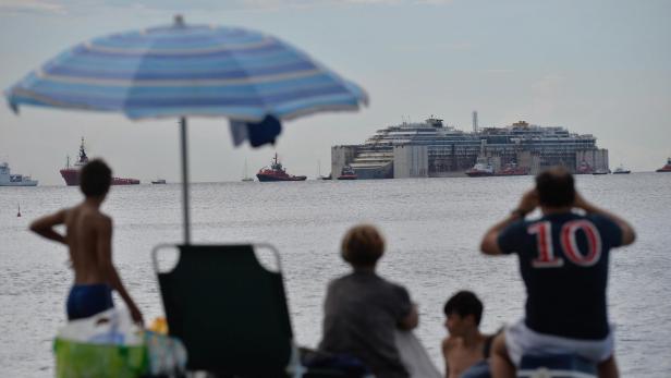 Menschen am Strand beobachten das teilweise versunkene Schiff Costa Concordia.