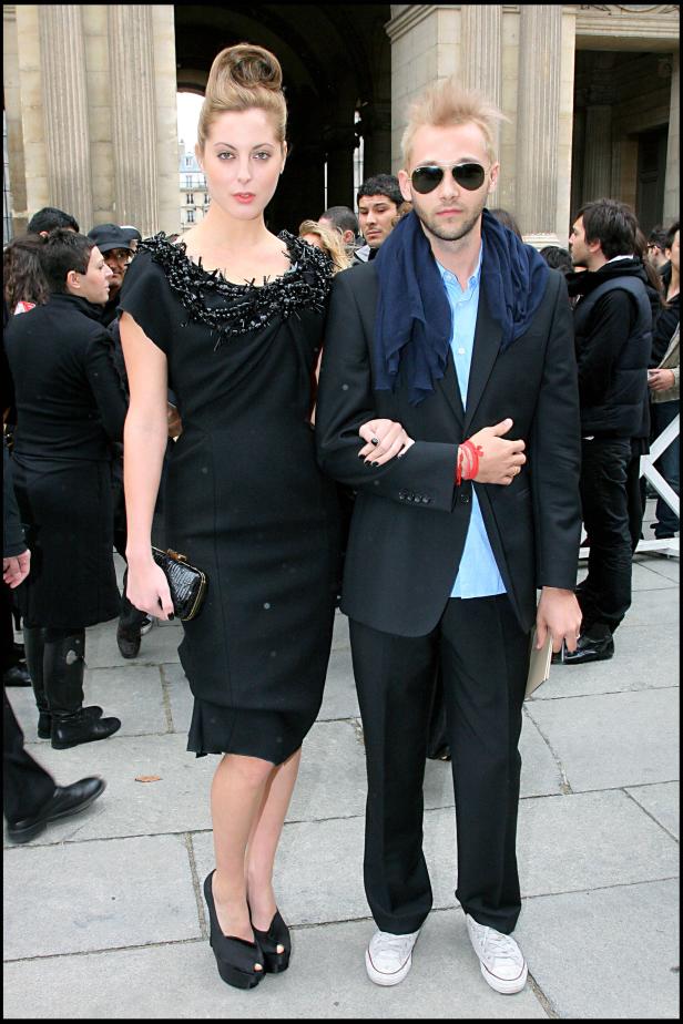 Eine Frau in einem schwarzen Kleid und ein Mann mit Sonnenbrille posieren für ein Foto.