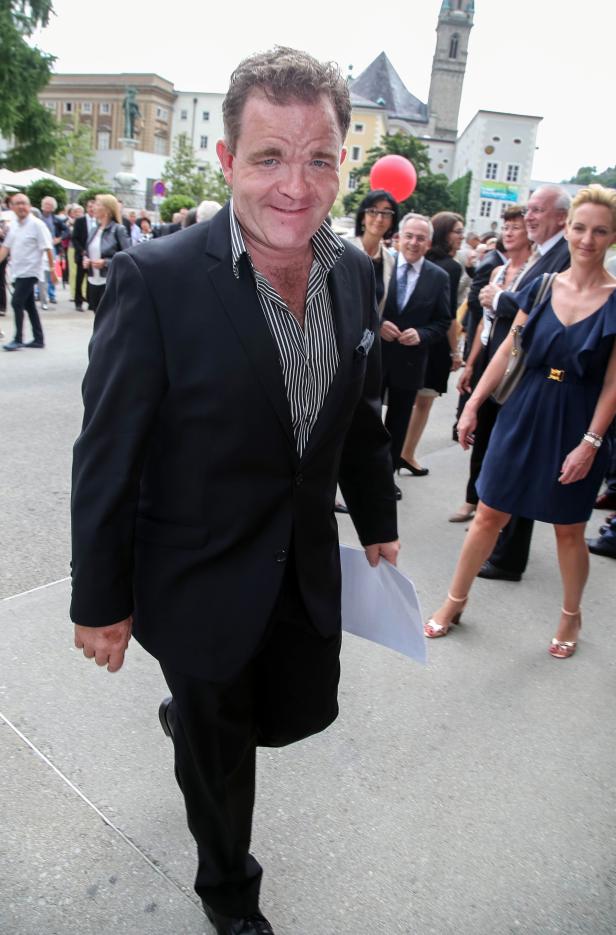 Ein Mann in einem Anzug geht an einer Menschenmenge vorbei.