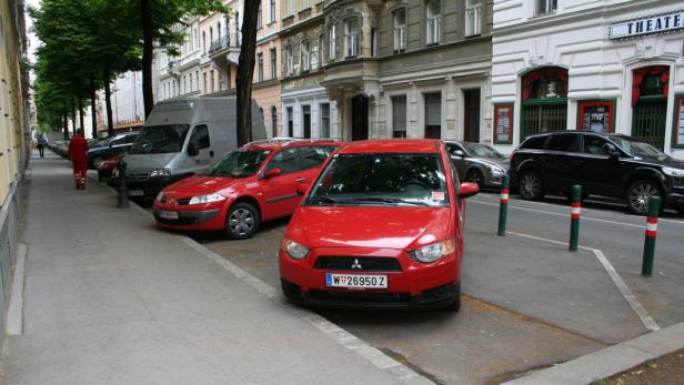 Ein roter Mitsubishi Colt parkt auf einer Straße in der Nähe eines Theaters.