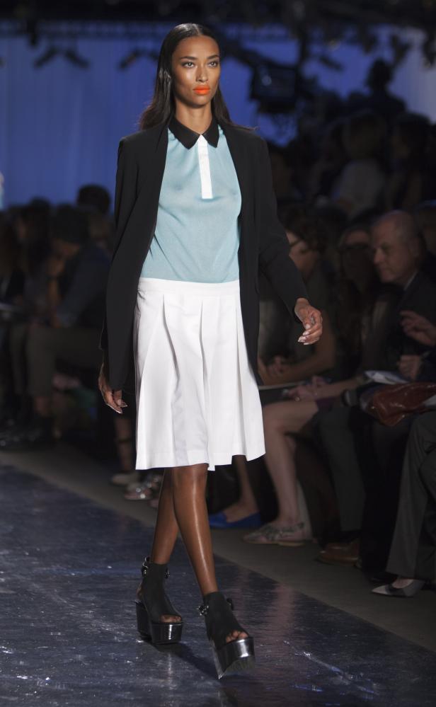 Eine Frau präsentiert Mode auf einem Laufsteg mit Plateauschuhen.